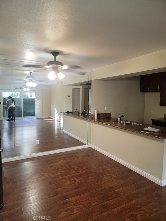 kitchen featuring dark hardwood / wood-style flooring, sink, dark brown cabinets, and dark stone countertops