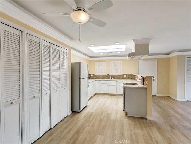 kitchen featuring white cabinetry, range, light hardwood / wood-style flooring, and white refrigerator