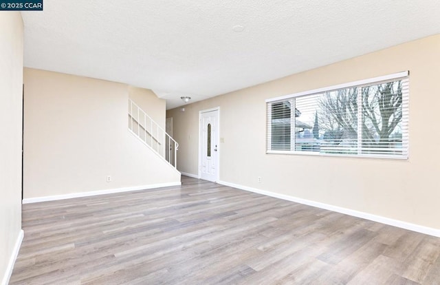 empty room with wood-type flooring and a textured ceiling