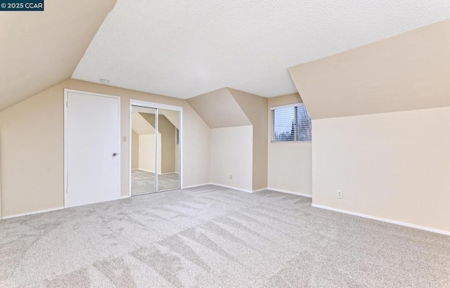 additional living space with lofted ceiling, light carpet, and a textured ceiling