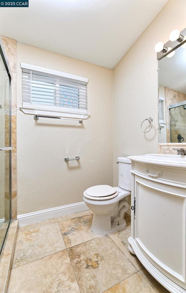 bathroom featuring a shower with door, vanity, and toilet