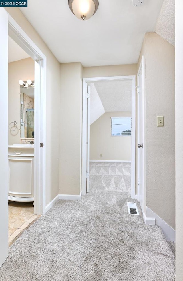 corridor with vaulted ceiling and light colored carpet