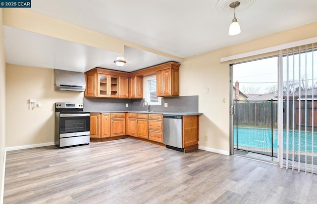 kitchen featuring sink, stainless steel appliances, extractor fan, decorative backsplash, and light wood-type flooring