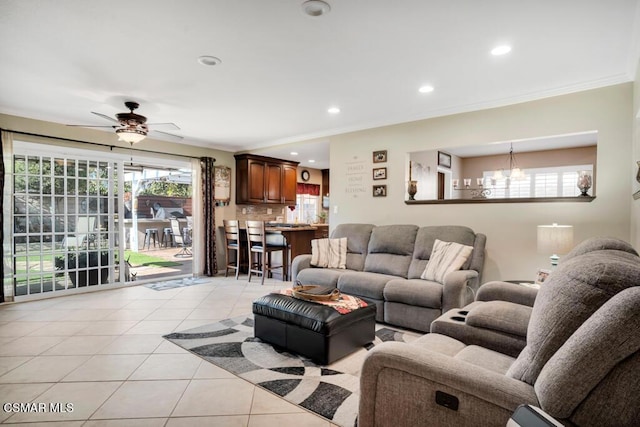 living room featuring light tile patterned floors, ceiling fan with notable chandelier, and ornamental molding