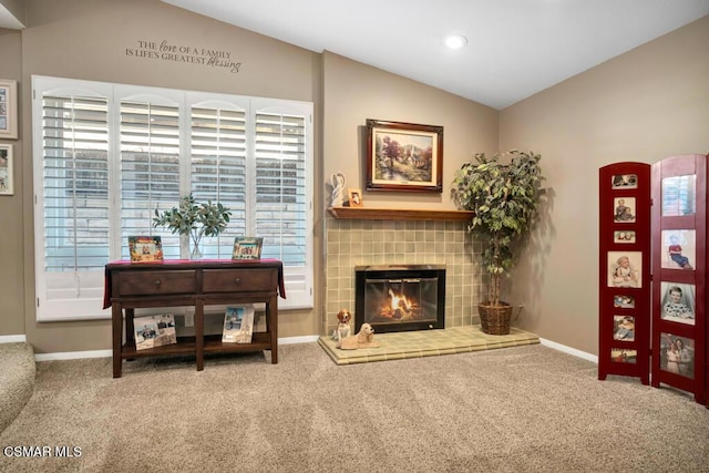 carpeted living room featuring vaulted ceiling and a tile fireplace