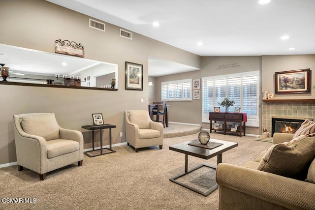 living room with lofted ceiling, light carpet, and a tile fireplace