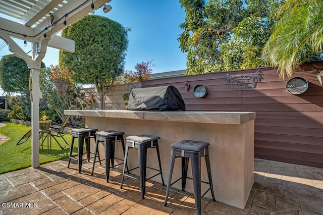 view of patio featuring exterior bar, grilling area, and a pergola