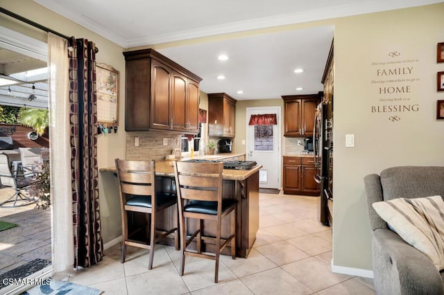 kitchen with tasteful backsplash, crown molding, plenty of natural light, and a breakfast bar