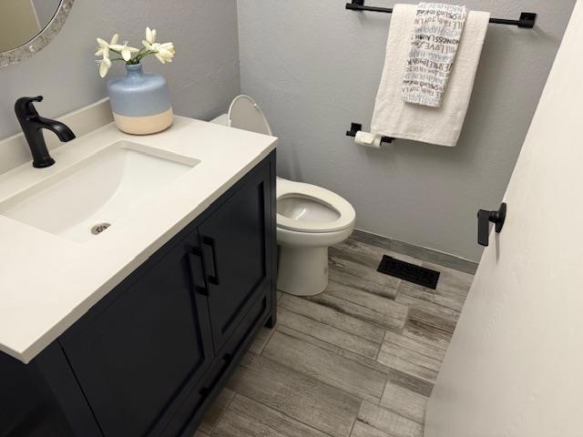 bathroom with vanity, wood-type flooring, and toilet