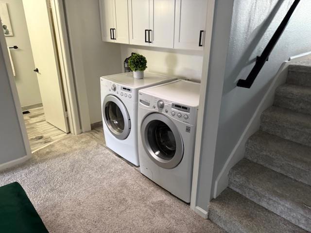 clothes washing area with light carpet and independent washer and dryer