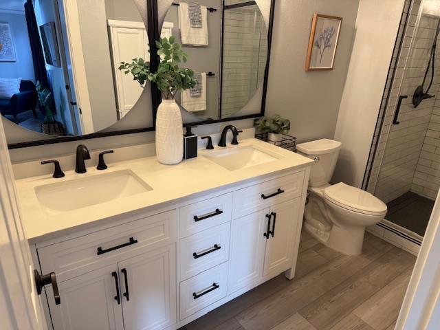 bathroom featuring vanity, toilet, an enclosed shower, and hardwood / wood-style floors