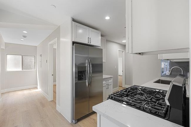 kitchen featuring white cabinetry, stainless steel fridge, sink, and light wood-type flooring