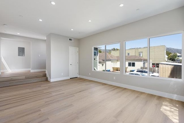 empty room with electric panel and light hardwood / wood-style flooring