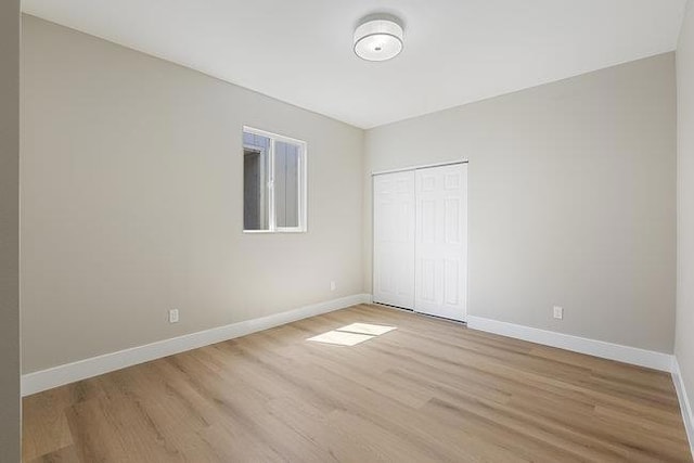 unfurnished bedroom with light wood-type flooring and a closet