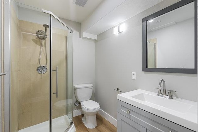 bathroom featuring wood-type flooring, toilet, an enclosed shower, and vanity