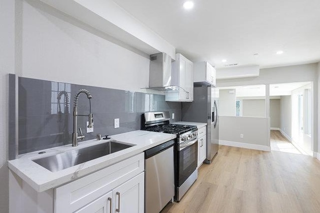 kitchen with appliances with stainless steel finishes, wall chimney exhaust hood, sink, and white cabinets