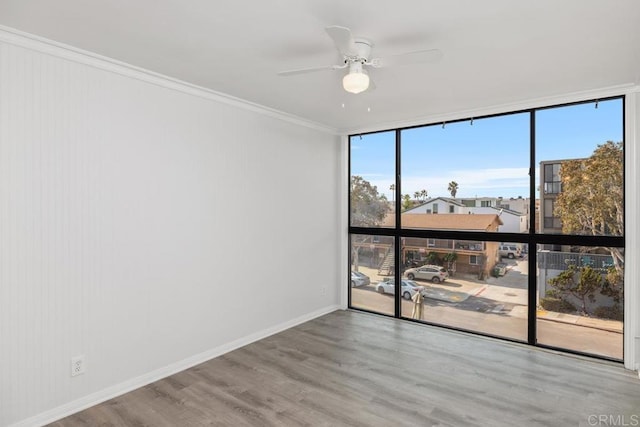 unfurnished room with hardwood / wood-style floors, crown molding, a wall of windows, and ceiling fan