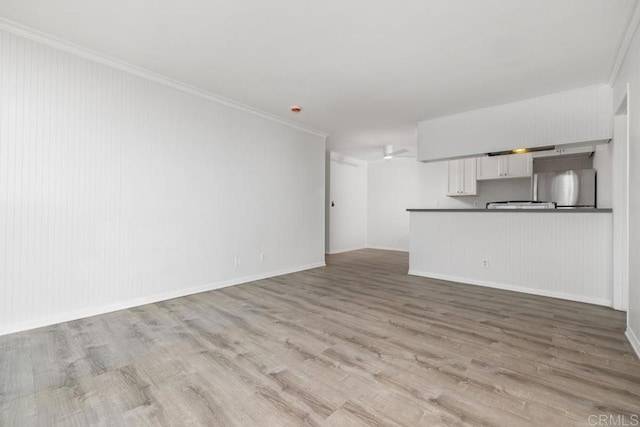 unfurnished living room featuring ornamental molding and light wood-type flooring