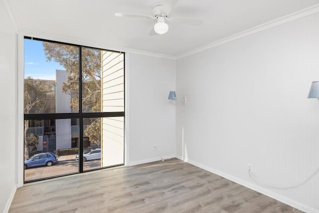 empty room featuring floor to ceiling windows, ceiling fan, crown molding, and light hardwood / wood-style flooring