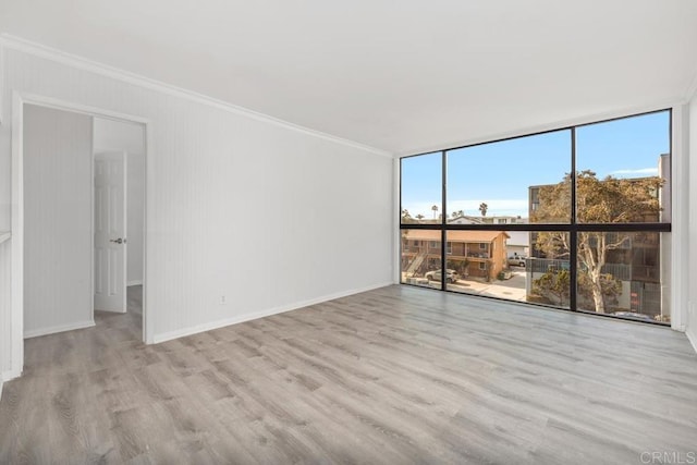 spare room featuring crown molding, light hardwood / wood-style floors, and floor to ceiling windows