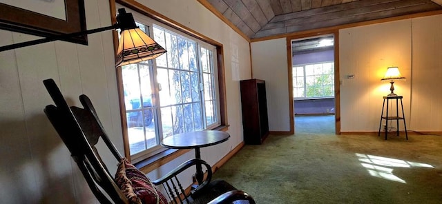 dining room with lofted ceiling, wood walls, and carpet flooring