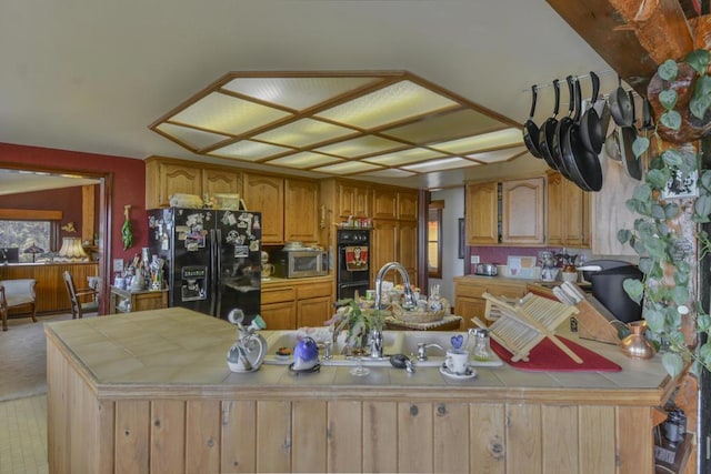 kitchen featuring tile countertops, kitchen peninsula, and black appliances