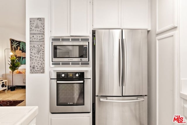 kitchen featuring tile countertops, stainless steel appliances, and white cabinets