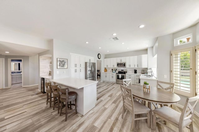 dining space with wine cooler, sink, and light hardwood / wood-style flooring