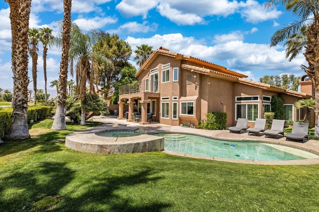 rear view of property featuring a swimming pool with hot tub, a patio, a balcony, and a lawn