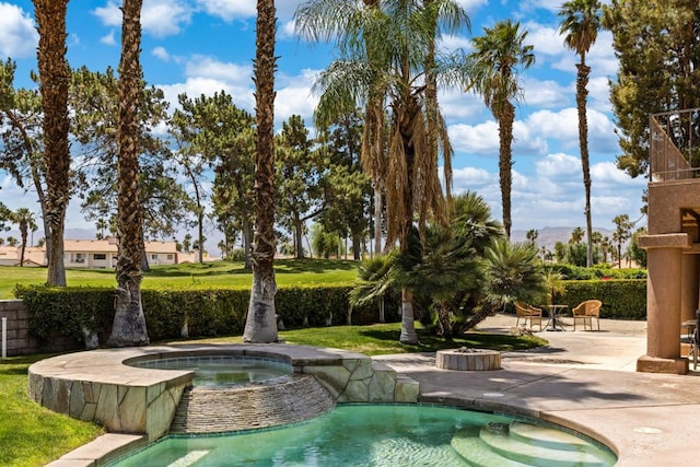 view of property's community with a hot tub and a patio area