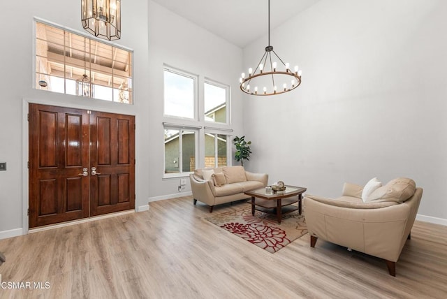 foyer with an inviting chandelier, a towering ceiling, and light hardwood / wood-style flooring