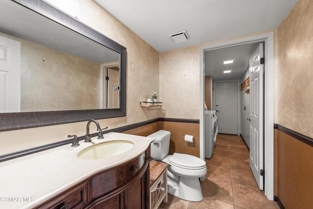 bathroom featuring independent washer and dryer, vanity, toilet, and tile patterned flooring