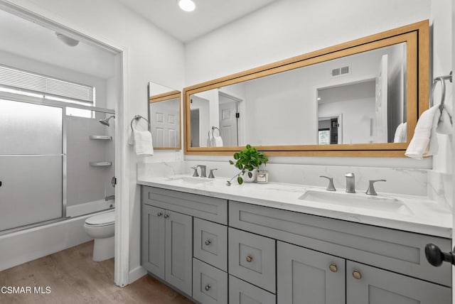 full bathroom with toilet, vanity, bath / shower combo with glass door, and hardwood / wood-style floors