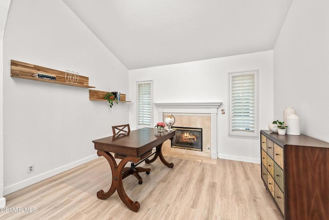 office area featuring a tile fireplace, lofted ceiling, and light wood-type flooring