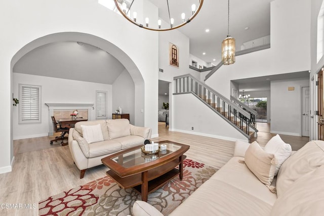 living room featuring a high ceiling, a chandelier, and light hardwood / wood-style floors