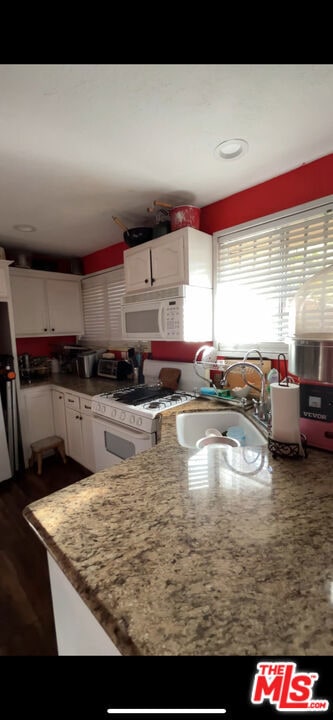 kitchen with white cabinetry, sink, light stone counters, and white appliances