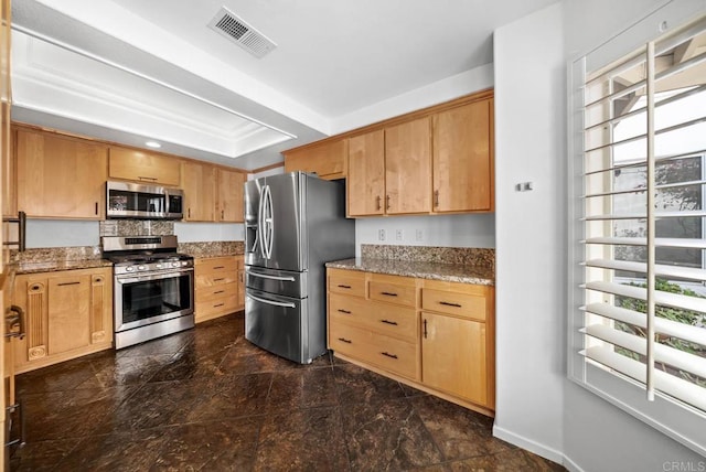 kitchen featuring baseboards, visible vents, a raised ceiling, light stone countertops, and stainless steel appliances