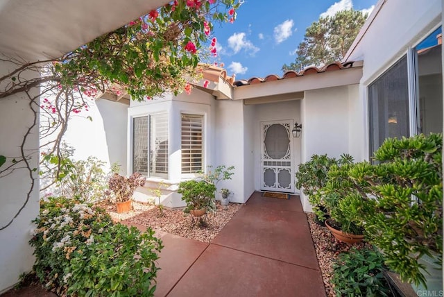 doorway to property with a tile roof and stucco siding