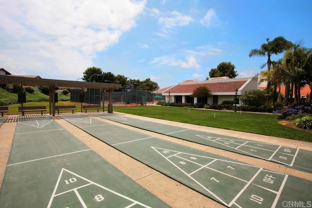 view of home's community with shuffleboard, fence, and a lawn