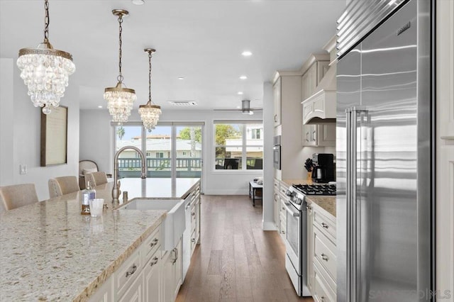 kitchen with a kitchen bar, light stone counters, decorative light fixtures, appliances with stainless steel finishes, and dark hardwood / wood-style floors