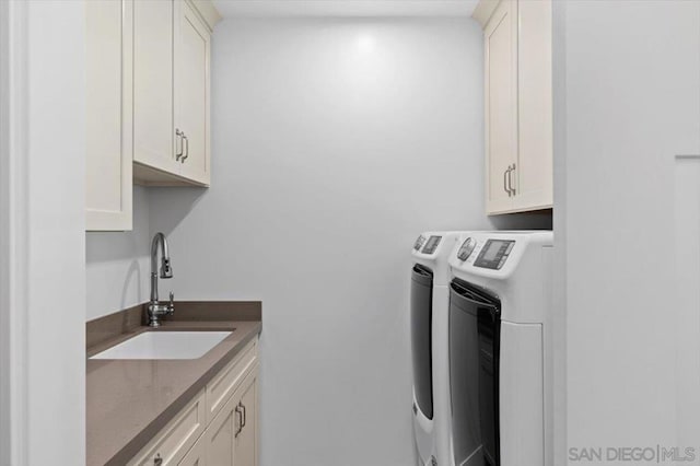 laundry area featuring washer and dryer, sink, and cabinets