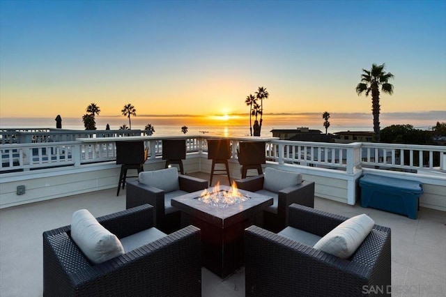 patio terrace at dusk featuring an outdoor living space with a fire pit and a water view