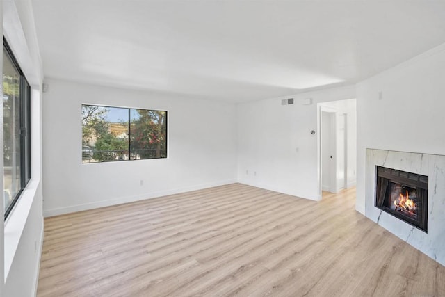 unfurnished living room featuring a tiled fireplace and light hardwood / wood-style floors