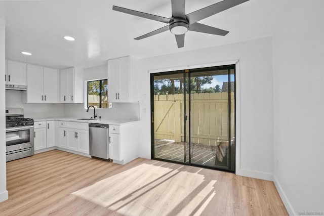 kitchen featuring sink, white cabinetry, backsplash, stainless steel appliances, and light wood-type flooring