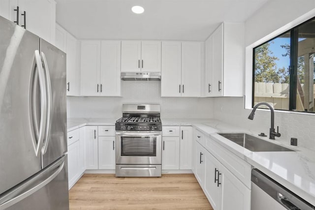 kitchen featuring white cabinetry, appliances with stainless steel finishes, sink, and light stone counters