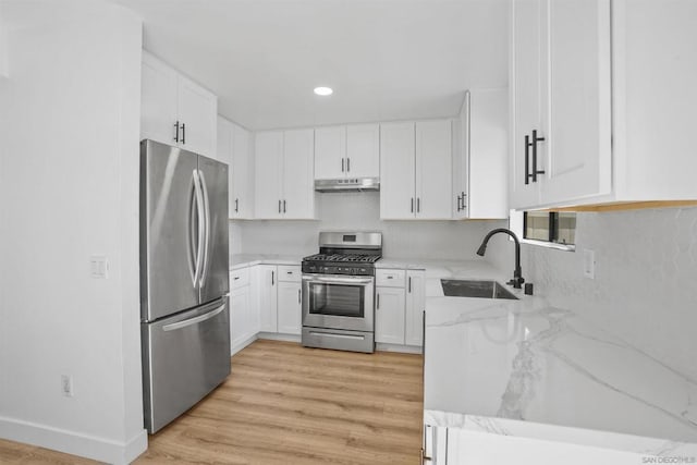 kitchen with sink, light stone counters, light wood-type flooring, appliances with stainless steel finishes, and white cabinets