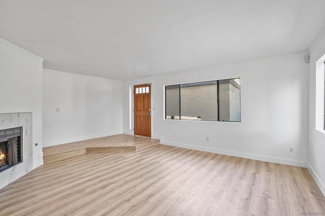 unfurnished living room with crown molding and light hardwood / wood-style floors