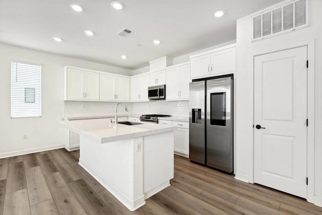 kitchen featuring a kitchen island with sink, sink, white cabinets, and appliances with stainless steel finishes