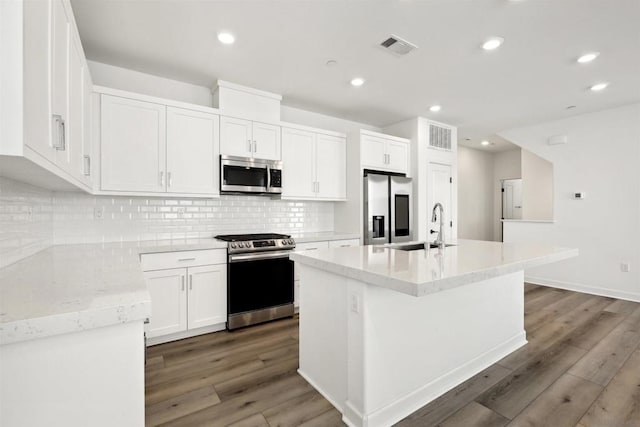 kitchen with dark wood-type flooring, sink, white cabinetry, an island with sink, and stainless steel appliances