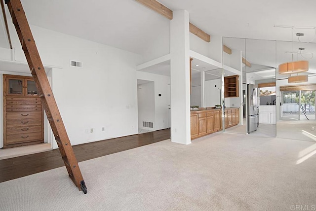 unfurnished living room with light carpet, high vaulted ceiling, and beamed ceiling